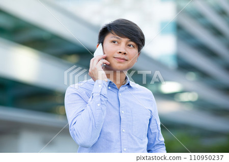 Young Korean guy makes business call via smartphone in city 110950237