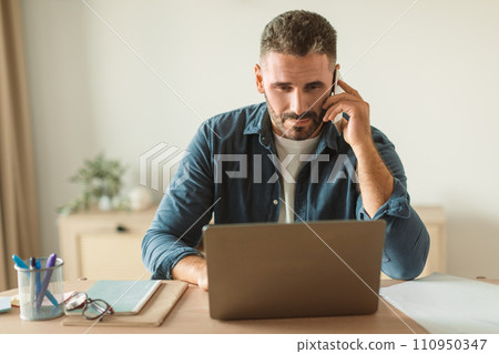businessman answering calls on mobile phone while using laptop indoor businessman answering calls on mobile phone while using laptop indoor 110950347