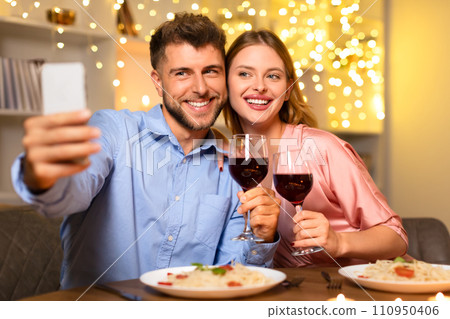 Happy couple taking selfie with wine during dinner 110950406