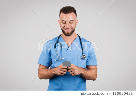 Cheerful young male nurse using smartphone and smiling 110950431