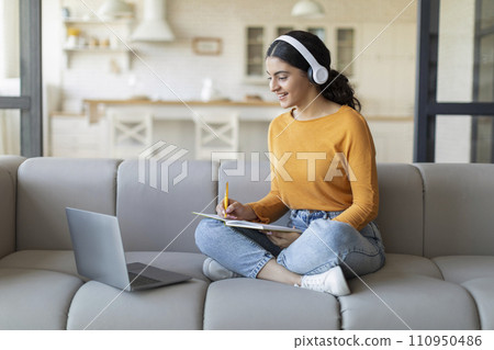 Young Indian Arab Woman In Headphones Study Online With Laptop From Home 110950486