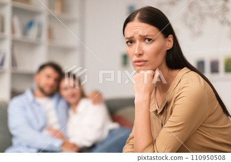 woman suffering from jealousy while man hugging another lady indoor 110950508