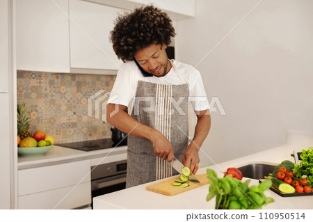 black guy talks on mobile phone while preparing lunch indoor 110950514