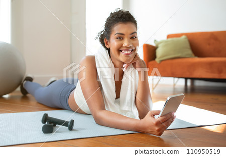 Sporty lady websurfing on phone resting during fitness workout indoor Sporty lady websurfing on phone resting during fitness workout indoor 110950519