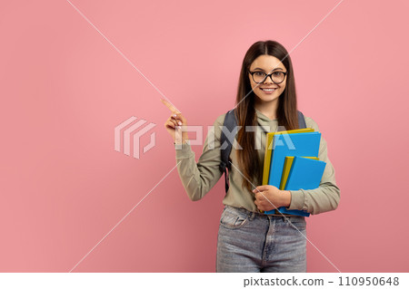 Happy teen girl holding books and pointing aside at copy space Happy teen girl holding books and pointing aside at copy space 110950648