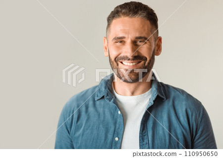 man beams with toothy smile posing against gray studio wall man beams with toothy smile posing against gray studio wall 110950650