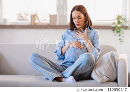 Pregnant lady feeling bad touching tummy and chest at home 110950847