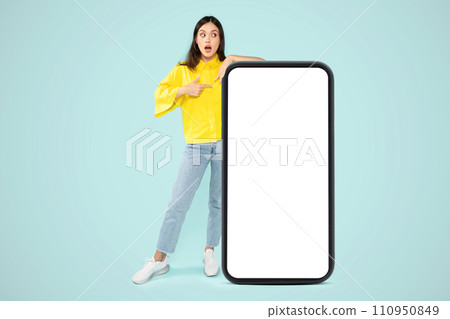Amazed young woman posing by huge phone, mockup 110950849