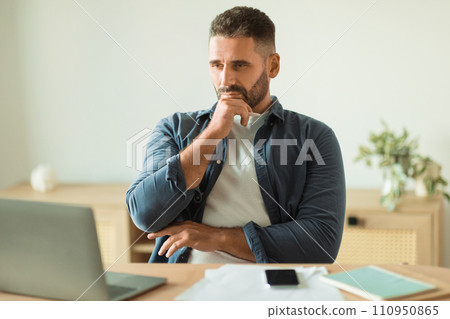 Pensive businessman sitting at laptop and table with papers indoor 110950865