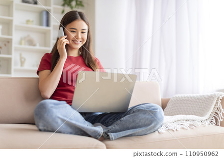 Remote Business. Asian Woman Talking On Phone And Using Laptop At Home 110950962