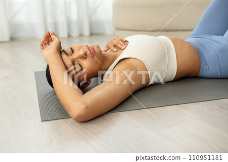 Unhappy tired young latin lady in sportswear doing exercises on mat, rest 110951181