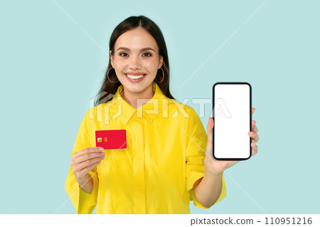 Happy young woman showing phone and credit card 110951216