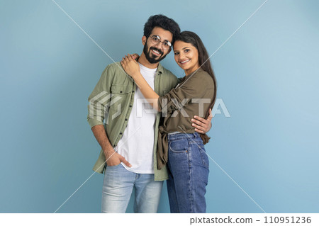 Beautiful millennial indian couple posing on blue studio background 110951236