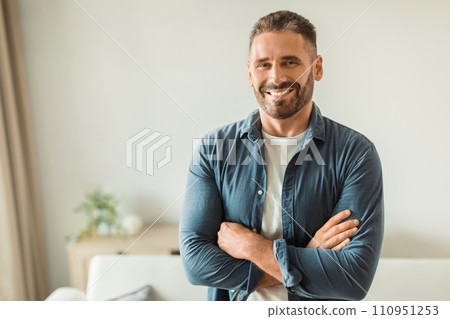 Cheerful middle aged man standing amidst modern living room Cheerful middle aged man standing amidst modern living room 110951253
