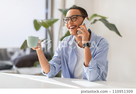 Joyful young woman in casual laughing, conversation on smartphone, hold cup 110951309