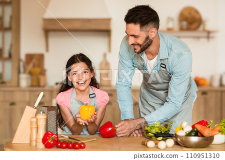 Father and daughter with bell pepper, cooking together 110951310