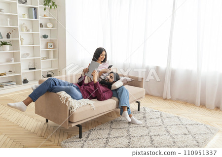 Relaxed indian couple using gadgets at home 110951337