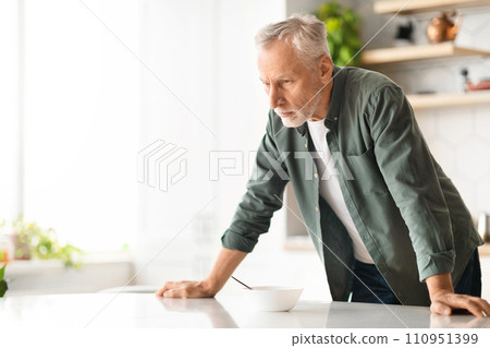 Portrait Of Depressed Elderly Man Leaning On Table In Kitchen Interior 110951399