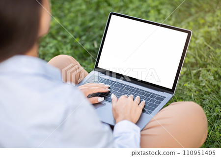 Young caucasian woman enjoy work, typing on laptop with empty screen, sit on grass Young caucasian woman enjoy work, typing on laptop with empty screen, sit on grass 110951405