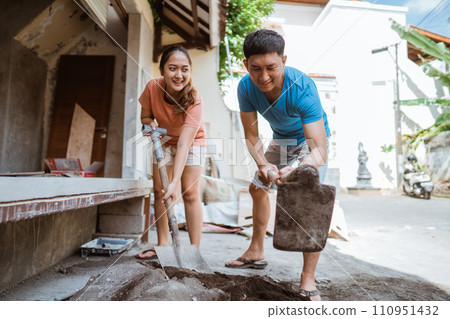 happy young husband and wife making cement mixture to build a house happy young husband and wife making cement mixture to build a house 110951432