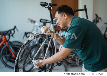 young man happily washing new bike with foaming soap with indoor background 110951503