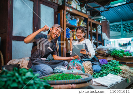vegetable sellers holding tablet with fist pump gesture 110951611