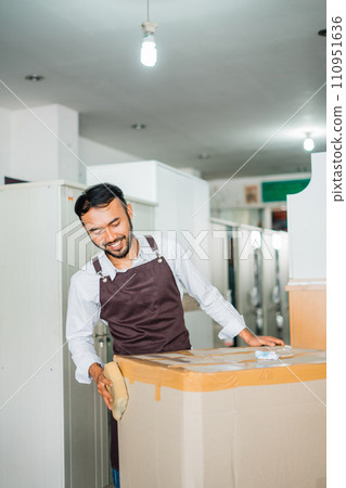 shop assistant man wrapping furniture using cardboard before sending it shop assistant man wrapping furniture using cardboard before sending it 110951636
