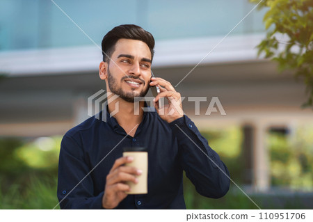 Arab entrepreneur man chatting on cellphone enjoying coffee break outside 110951706