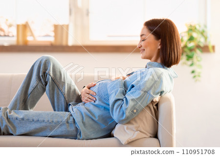 Joyful pregnant lady relaxing on couch and anticipates motherhood indoors 110951708