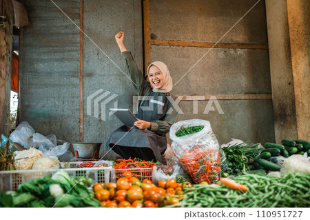 asian vegetable seller holding tablet with fist pump gesture 110951727
