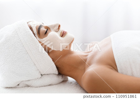 Side view indian woman applying facial clay mask at spa Side view indian woman applying facial clay mask at spa 110951861