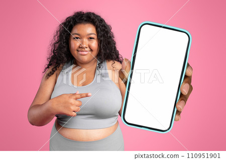 black woman in sportswear showing big phone over pink backdrop 110951901