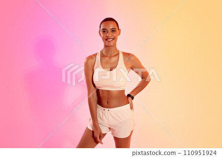Glad slim young latin lady athlete in sportswear ready to workout on neon pink studio background 110951924