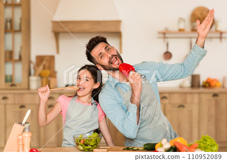 Joyful dad and girl singing with veggies Joyful dad and girl singing with veggies 110952089