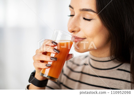 Happy young arab woman drink glass of fresh tasty juice in room interior, close up Happy young arab woman drink glass of fresh tasty juice in room interior, close up 110952098