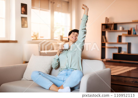 Joyful lady in modern living room enjoying break and coffee 110952113