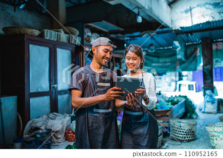 couple greengrocery sellers standing and holding tablet couple greengrocery sellers standing and holding tablet 110952165