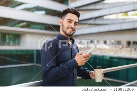 Young Arabic businessman using his phone gadget in urban area Young Arabic businessman using his phone gadget in urban area 110952209