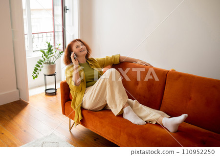 Happy Senior Woman Talking On Cellphone While Relaxing On Couch At Home, Happy Senior Woman Talking On Cellphone While Relaxing On Couch At Home, 110952250