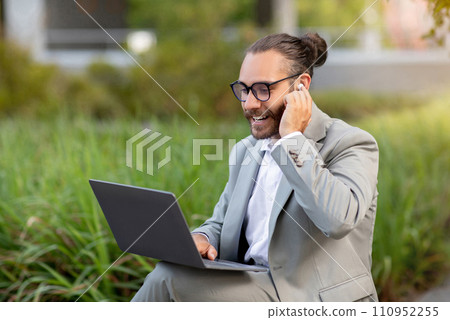 Millennial businessman teleconferencing via laptop while working outdoors 110952255