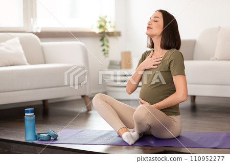 Pregnant woman practices prenatal yoga focusing on breathing exercises indoor 110952277