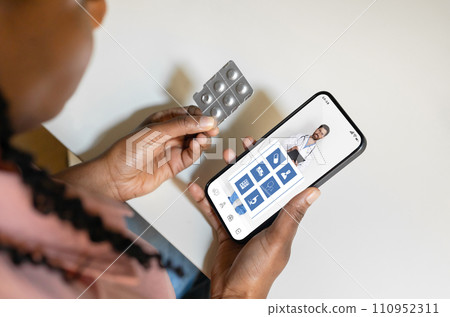 Black woman at home accessing an online medical app on her smartphone 110952311