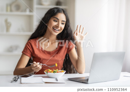 Cheerful millennial indian woman have lunch break at home office Cheerful millennial indian woman have lunch break at home office 110952364