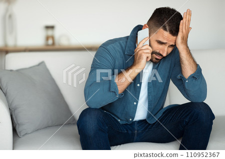 Middle aged man talks on phone displaying stress indoor 110952367