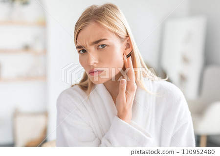woman examines face skin for blackheads and wrinkles in bathroom woman examines face skin for blackheads and wrinkles in bathroom 110952480