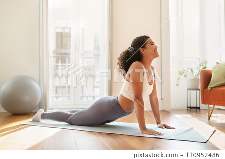 Young lady doing upward facing dog pose practicing yoga indoors 110952486