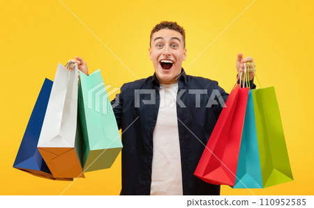 Happy young man going shopping, holding bags and looking excited 110952585