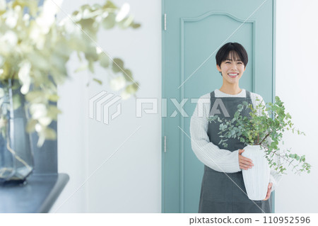 A woman watering houseplants 110952596