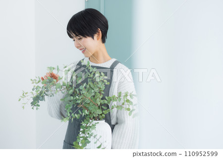 A woman watering houseplants 110952599