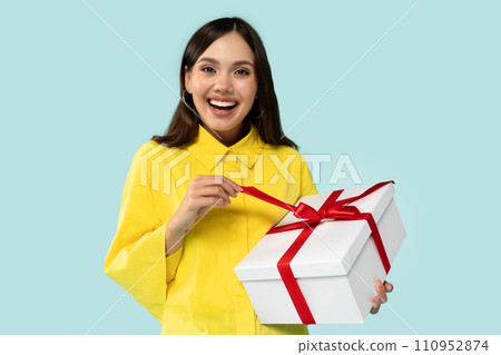 Positive cheerful young brunette lady holding wrapped gift box Positive cheerful young brunette lady holding wrapped gift box 110952874